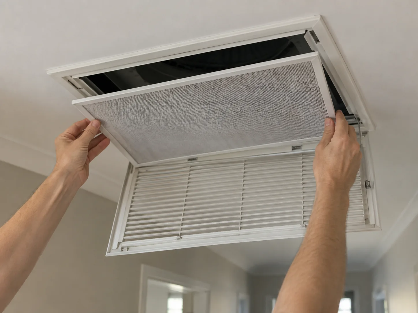 A hinged return air grille in a hallway ceiling opened to show the filter
