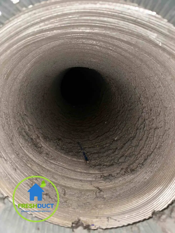Inside a Melbourne air duct caked in thick grey dust before cleaning