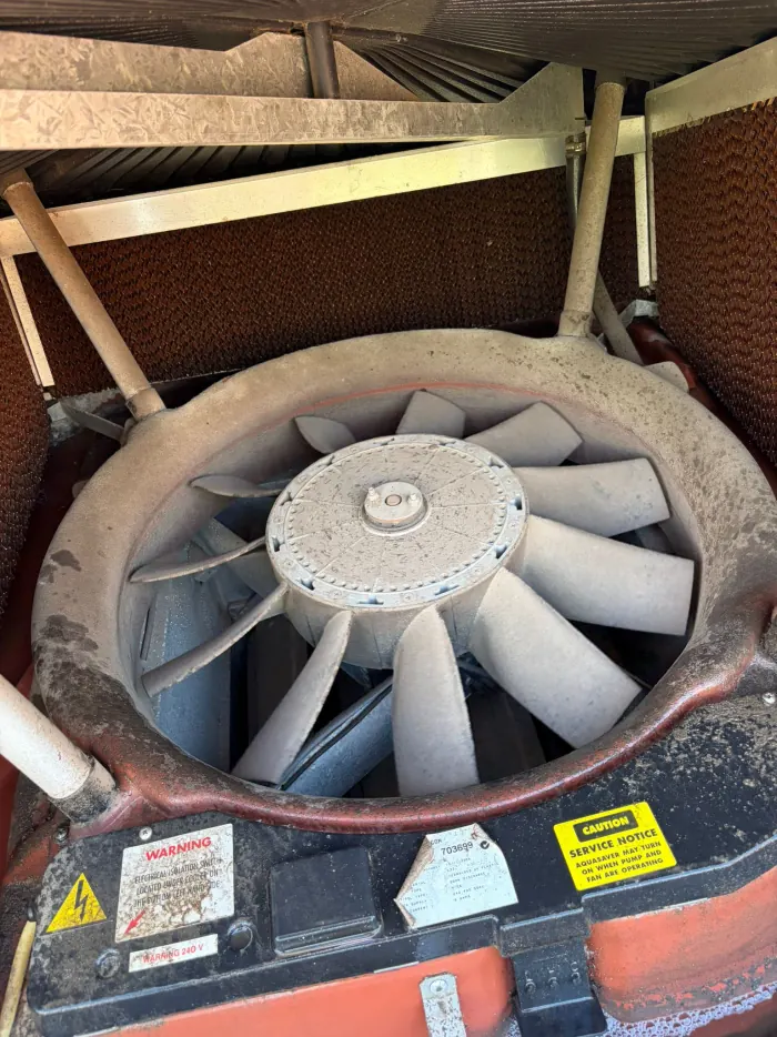 Evaporative cooler fan covered in mineral scale and dust before cleaning